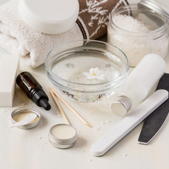Fototapeta na wymiar Hand and nail care products. Sea salt. nourishing cream, a variety of nail files, essential oil and a terry towel on a light wooden background.