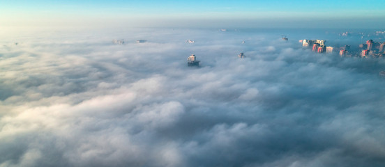 The city is covered with thick fog and protruding from it where neither where high-rise buildings © LALSSTOCK