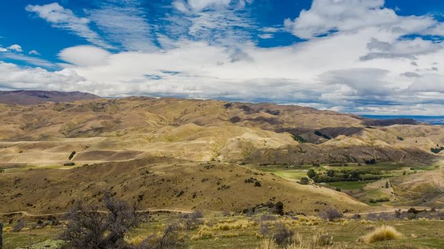 Landscape of arid hills in timelapse video on sunny summer day with white patches of clouds flying above the countryside. Shot on South Island, New Zealand