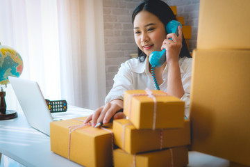 women telephone contact with customer for shopping online of own businessat home office packaging on background is a popular business. online shopping SME entrepreneur or freelance working concept
