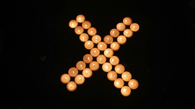 X-shape made from candle light, time lapse.