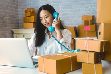 Business woman owner calling to customer for confirm order and address before sent box. Freelance woman working at home with online parcel delivery. E-commerce business owner or SME concept.