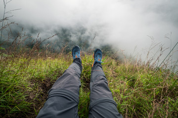 Legs of traveler sitting on a high mountain. Freedom concept