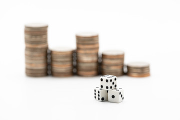 Dice in front of coins stacks. Financial, risk, chance, and business opportunity concept.