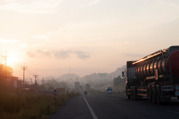 The journey of the vehicle in the morning on highway with Morning sun and fog.