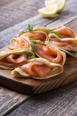 Smoked salmon appetizer, stuffed crepes on wooden board
