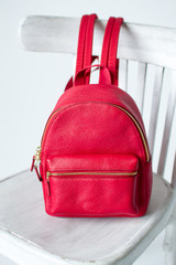 red leather backpack on white wooden chair, womens leather backpack, the front of the red rucksack