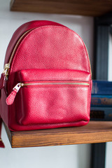 red leather backpacks on wooden bookcase shelf, womens leather backpacks, the front of the red rucksack