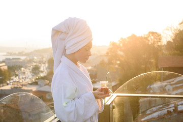 A girl in a bathrobe with a cup of Turkish tea at sunrise on the terrace of a house in Istanbul