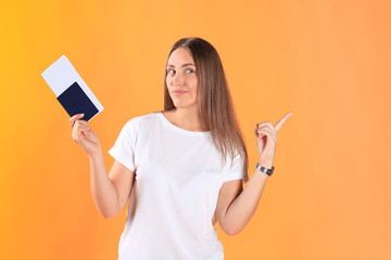 Naklejka premium Excited young woman tourist standing isolated on yellow background holding passport with tickets.