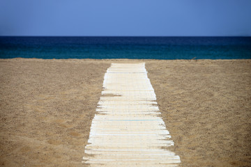 Wooden path over the sand of Spiaggia della Piscinas beach, Sardinia island, Italy