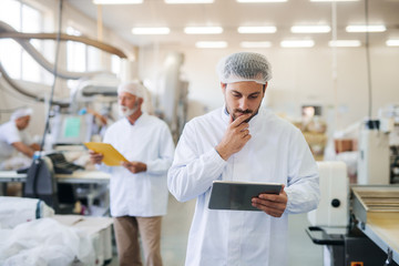 Man standing and holding tablet.