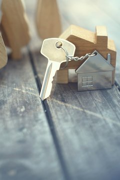 Home key with house keychain and wooden treen and home mock up on vintage wood background, property concept