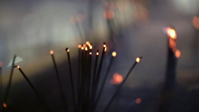 Video recording of smoldering aroma sticks in dark interior of buddhist temple