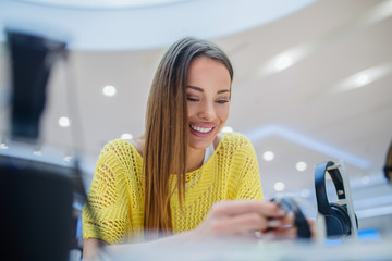 Smiling woman choosing what to buy in tech store. Technology shopping concept.