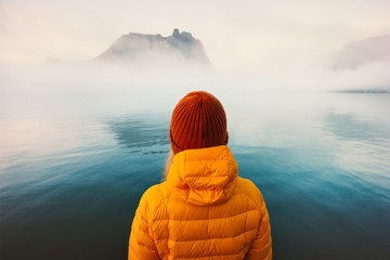 Woman alone looking at foggy cold sea traveling adventure lifestyle outdoor solitude emotions...