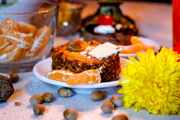 Beautiful evening composition with cakes and candle light.Old candle holder, flowers, cakes, oranges, limon, red orange juice, walnuts and hazelnuts.