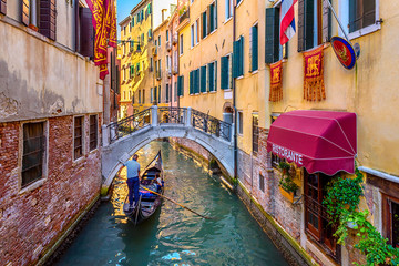 Fototapeta na wymiar Narrow canal with gondola and bridge in Venice, Italy. Architecture and landmark of Venice. Cozy cityscape of Venice.