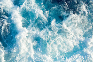 Fototapeta na wymiar Spalsh of a blue sea water behind a ship.