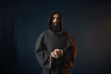 Medieval monk holds cross in hands and praying - obrazy, fototapety, plakaty
