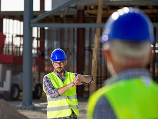 Two engineers gesturing at building site