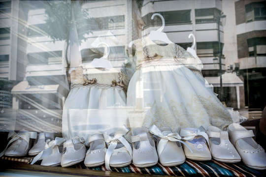 Dresses and shoes to make first communion reflected in showcase, conceptual image