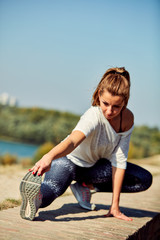 Fototapeta na wymiar Portrait of sporty young woman doing stretching in city.