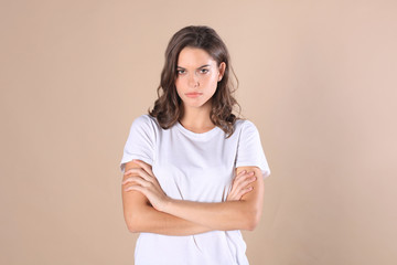 Fototapeta premium Cheerful brunette woman dressed in basic clothing looking at camera, isolated on beige background.