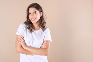 Fototapeta premium Cheerful brunette woman dressed in basic clothing looking at camera, isolated on beige background.