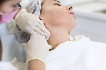 Obraz na płótnie Canvas Cosmetologist makes a mesotherapy procedure and Microcurrent therapy of a adult woman in a beauty salon. Hardware Cosmetology and professional skin care.