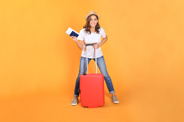 Young tourist girl in summer casual clothes, with red suitcase, passport, tickets isolated on beige background.