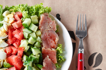 cobb salad - traditional american food,  hearty meal of salmon, eggs, cucumber, avocado and lettuce leaves with mustard dressing, top view