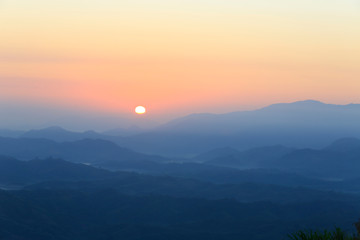 Mountain valley in misty day with red sun