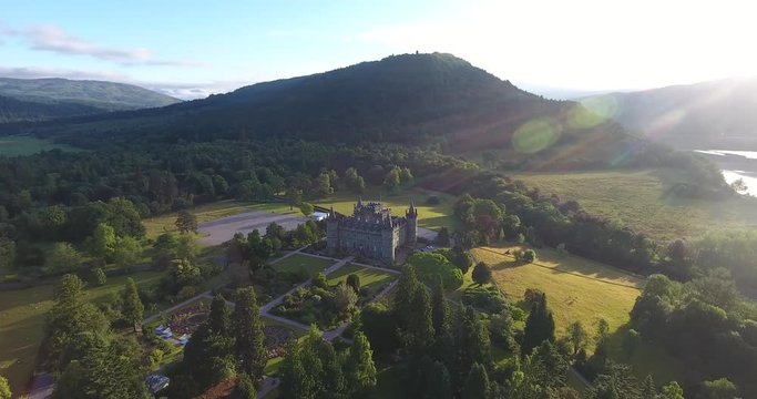 Scottish Hill Aerial Drone Pulling Back over Morning Countryside and Village - Inveraray Castle