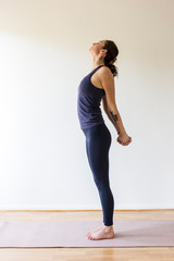Fototapeta na wymiar young woman stands in blue yoga outfit stretching