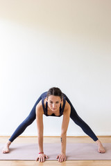 young woman doing yoga exercise aide-legged forward bend asana