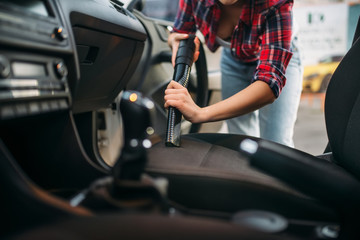 Woman cleans car interior with vacuum cleaner