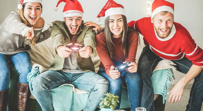 Group of happy friends having fun with video games console on christmas time