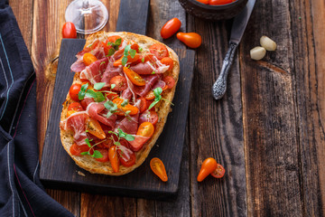 Italian bruschetta with prosciutto, tomato and basil, copy space.