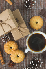 Cup of hot coffee with pastry, new year packs and pine cones