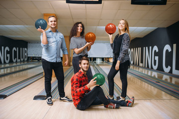 Fototapeta na wymiar Bowling team poses on lane with balls on hands
