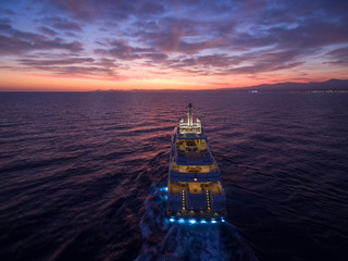 A huge luxury motor yacht goes in the direction of the sunset