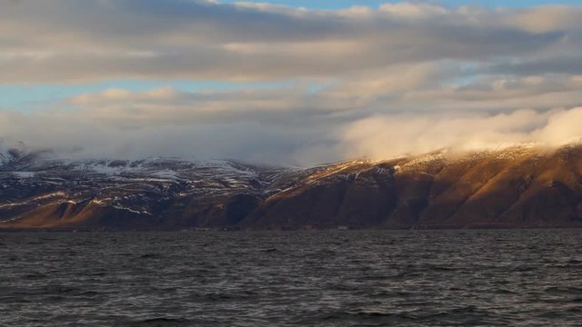 Daytime Timelapse of moving white clouds over lake Sevan on background hills.