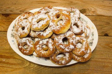 Sweet, flavorful donuts in powder in a plate on a wooden table