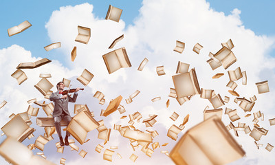Handsome violinist sitting on book and play his melody