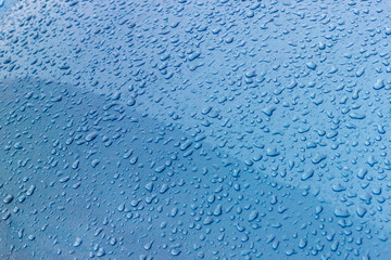 Water drops on the metal blue surface of the car