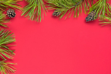 Christmas decor with copy space on a colored background top view. New Year, holiday, give, pine brunches and cones. flatlay, red background