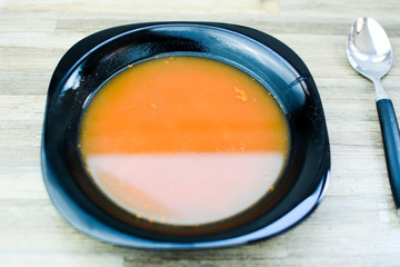 Red tomato soup in the kitchen with black plate.
