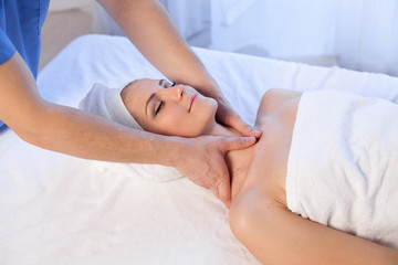 a massage therapist makes a woman face and neck massage in the Spa