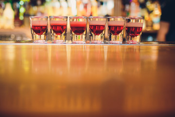 Bartender is pouring tequila into glass against the background of the bar.